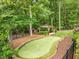 Well-manicured backyard with a putting green, gazebo, and black metal fencing bordering the property at 410 Mountain Laurel, Chapel Hill, NC 27517