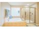 Bright bathroom featuring a garden tub next to a frosted window and a standing glass shower at 508 E Hatterleigh Ave, Hillsborough, NC 27278