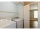 Well-lit laundry room with white washer and dryer, storage shelves, and wood floor at 518 S Coalport Dr, Apex, NC 27502