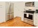 Kitchen with stainless steel appliances, white cabinets, granite countertops, and hardwood floors at 5304 Cypress Ln, Raleigh, NC 27609