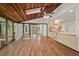 Open-concept living room featuring wood floors, beamed wood ceiling with skylight, and views to the backyard at 6321 Malvern Ln, Hillsborough, NC 27278