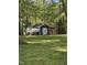 Exterior view of a backyard shed with an overhang surrounded by trees and flowers at 6321 Malvern Ln, Hillsborough, NC 27278