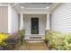 Close-up of a home's front entrance with a dark door framed by white pillars and lush landscaping at 65 Cattail Ln, Zebulon, NC 27597