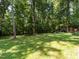 Expansive green backyard surrounded by mature trees and a small outbuilding at 6760 Keansburg Rd, Gibsonville, NC 27249