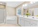 Bright bathroom with a large tub, white cabinetry, dual sinks and a window providing natural light at 7021 Oviedo Dr, Raleigh, NC 27603