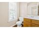 Clean half bathroom with a classic vanity, toilet, and a bright window for natural light at 7021 Oviedo Dr, Raleigh, NC 27603