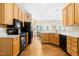 Traditional kitchen featuring wood cabinets, black appliances, and hardwood flooring at 7021 Oviedo Dr, Raleigh, NC 27603