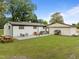 Home's backyard features a cozy patio, well-maintained lawn, mature trees, and connection to the outbuilding at 7042 Us 401 Highway N, Fuquay Varina, NC 27526