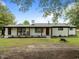 Charming white brick home boasts a covered porch with wooden columns, inviting rocking chairs, and beautifully landscaped front yard at 7042 Us 401 Highway N, Fuquay Varina, NC 27526