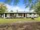 Charming white brick home boasts a covered porch with wooden columns, inviting rocking chairs, and beautifully landscaped front yard at 7042 Us 401 Highway N, Fuquay Varina, NC 27526