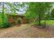 The backyard features mature trees and landscaping with brick home in the background at 720 Sherrybrook Dr, Raleigh, NC 27610