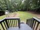 View from a back deck looking out onto a large lawn with a wooden fence, shed, and wooded area at 8116 Reynard Rd, Chapel Hill, NC 27516