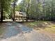 A serene setting showcases a home with a classic covered porch along a tree lined driveway at 8116 Reynard Rd, Chapel Hill, NC 27516