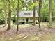 Home with a covered front porch, framed by mature trees and established landscaping in a woodland setting at 8116 Reynard Rd, Chapel Hill, NC 27516