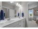 Bright bathroom featuring double sinks, white cabinets, and a view into a bedroom at 821 Rambling Oaks Ln, Holly Springs, NC 27540