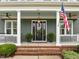 Inviting front porch with brick steps, white columns, ceiling fans, and a classic front door at 821 Rambling Oaks Ln, Holly Springs, NC 27540