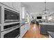 Open kitchen with stainless steel appliances, white cabinets, granite countertops, and view into living room at 821 Rambling Oaks Ln, Holly Springs, NC 27540