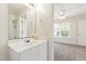 Bathroom with white vanity and mirror, leading to carpeted bedroom with ceiling fan and window at 929 Morreene Rd # C31, Durham, NC 27705