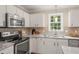 View of the kitchen featuring granite countertops, tile backsplash, stainless steel appliances and white cabinets at 110 Benedum Pl, Cary, NC 27518