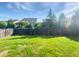Backyard with a wooden fence and lush green grass, bordered by mature trees, plants, and neighboring homes at 120 Martingale Dr, Holly Springs, NC 27540