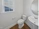 Well-lit half bathroom featuring a toilet and sink with modern fixtures at 120 Martingale Dr, Holly Springs, NC 27540