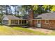 Brick ranch house with a well-maintained lawn, mature trees, and a screened-in porch at 129 Castle Dr, Smithfield, NC 27577