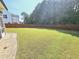A spacious backyard with healthy green grass, wooden fencing, mature trees, and a stone patio at 1412 Queen Trigger Dr, Fuquay Varina, NC 27526