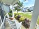 Inviting front porch featuring two white rocking chairs surrounded by colorful landscaping and decorative plantings at 1412 Queen Trigger Dr, Fuquay Varina, NC 27526