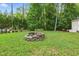 Backyard fire pit, surrounded by greenery, offers a cozy outdoor gathering space at 153 Hickory Nut Dr, Smithfield, NC 27577