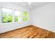 Bright bedroom featuring hardwood floors, a ceiling fan, and three large windows with a green view at 1621 Ella Wiggins Way, Raleigh, NC 27603