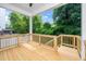 Covered wooden deck with light-colored railings and stairs, offering a view of the lush, green backyard at 1621 Ella Wiggins Way, Raleigh, NC 27603