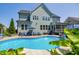 Backyard swimming pool and patio with lounge chairs, umbrellas, BBQ grill and lush foliage at 205 Silent Cove Ln, Holly Springs, NC 27540