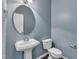 Powder room featuring a pedestal sink, round mirror, and a modern toilet at 211 Westgrove Ct, Durham, NC 27703