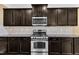 A kitchen features dark cabinets, stainless steel oven/stove and a tiled backsplash for a modern appeal at 211 Westgrove Ct, Durham, NC 27703