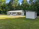 Charming home with lush lawn, new concrete driveway, and modern shed is nestled amongst mature trees on a sunny day at 2210 Pilot-Riley Rd, Zebulon, NC 27597
