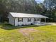 A bright exterior view of the house, featuring a metal roof, landscaping, and updated paint at 2210 Pilot-Riley Rd, Zebulon, NC 27597