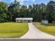 A charming white house with a well-manicured lawn, concrete driveway, and modern storage shed set in a verdant landscape at 2210 Pilot-Riley Rd, Zebulon, NC 27597