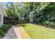 Private backyard features a stone patio, gravel area, lush lawn, mature trees, and a wooden fence for added seclusion at 2225 Creston Rd, Raleigh, NC 27608