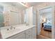 Bathroom with double sinks, floral wallpaper, and a view into the bedroom through an open doorway at 2225 Creston Rd, Raleigh, NC 27608