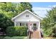 Charming white cottage with brick steps, lush landscaping, and an American flag at 2225 Creston Rd, Raleigh, NC 27608