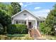 Charming white cottage with brick steps, lush landscaping, and manicured bushes at 2225 Creston Rd, Raleigh, NC 27608