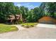 Log home with detached garage, brick walkway, and green lawn, embraced by a lush green forest at 2416 Kearney Rd, Wake Forest, NC 27587