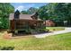 Inviting log home with a cozy porch, stone foundation, green lawn, and convenient garage at 2416 Kearney Rd, Wake Forest, NC 27587