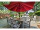 Backyard patio features a stone surface, a large red umbrella over a table with chairs, and lush landscaping at 308 W Whitaker Mill Rd, Raleigh, NC 27608