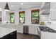 Open kitchen showcasing white cabinets, stone counters, stainless steel appliances, and multiple windows at 308 W Whitaker Mill Rd, Raleigh, NC 27608
