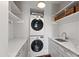 Bright laundry room featuring stacked washer and dryer, marble countertops, white cabinets, and sink at 308 W Whitaker Mill Rd, Raleigh, NC 27608