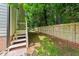 Backyard featuring a wooden fence, steps to a side door, and mature trees at 413 Top Greene Ln, Raleigh, NC 27601