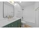 Bathroom with stylish green vanity, gold fixtures, and tiled shower and tub combo at 413 Top Greene Ln, Raleigh, NC 27601