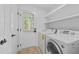 Well-lit laundry room with appliances, shelving, and door to the outside at 413 Top Greene Ln, Raleigh, NC 27601