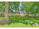 Large backyard with lush green grass, shady trees, patio and a storage shed on a sunny day at 422 Hyde St, Burlington, NC 27217